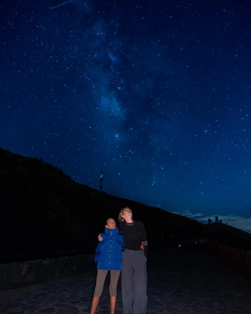 Due donne su una strada di montagna di notte, sotto un cielo stellato con la Via Lattea